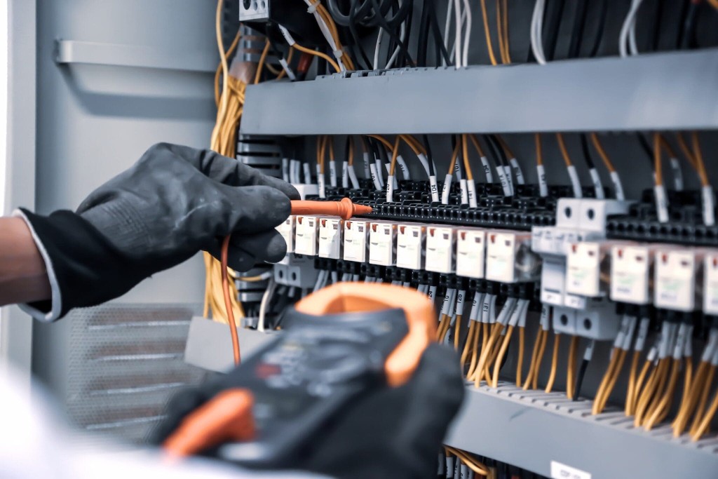 Electrical engineer testing cables on an industrial control panel